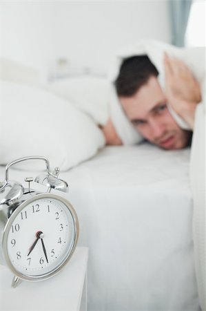 simsearch:6109-06194878,k - Portrait of a young man covering his ears with a duvet while his alarm clock is ringing in his bedroom Stock Photo - Budget Royalty-Free & Subscription, Code: 400-05737287