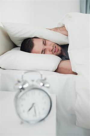 simsearch:6109-06194878,k - Portrait of a exhausted young man covering his ears while his alarm clock is ringing in his bedroom Stock Photo - Budget Royalty-Free & Subscription, Code: 400-05737289