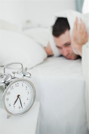 simsearch:6109-06194878,k - Portrait of a exhausted man covering his ears while his alarm clock is ringing in his bedroom Stock Photo - Budget Royalty-Free & Subscription, Code: 400-05737283