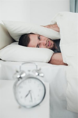 simsearch:6109-06194878,k - Portrait of a tired young man covering his ears while his alarm clock is ringing in his bedroom Stock Photo - Budget Royalty-Free & Subscription, Code: 400-05737290