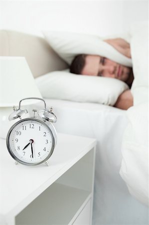 simsearch:6109-06194878,k - Portrait of a tired young man covering his ears with a pillow while his alarm clock is ringing Stock Photo - Budget Royalty-Free & Subscription, Code: 400-05737357
