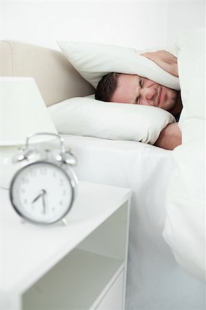 simsearch:6109-06194878,k - Portrait of a young man covering his ears with a pillow while his alarm clock in ringing Stock Photo - Budget Royalty-Free & Subscription, Code: 400-05737351