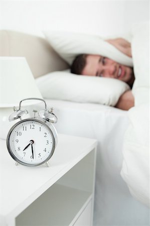 simsearch:6109-06194892,k - Portrait of a exhausted man covering his ears with a pillow while his alarm clock is ringing Foto de stock - Super Valor sin royalties y Suscripción, Código: 400-05737353