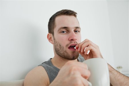 simsearch:400-05716904,k - Young man taking a pill in his bedroom Stock Photo - Budget Royalty-Free & Subscription, Code: 400-05737434