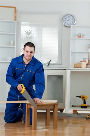simsearch:700-02071118,k - Portrait of a smiling handyman cutting a wooden board in a kitchen Stock Photo - Budget Royalty-Free & Subscription, Code: 400-05737683