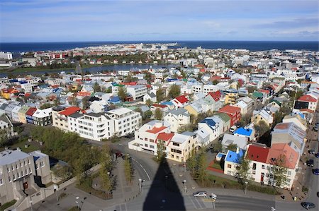 View over the city of Reykjavik seen from the top of the tower of Hallgrimur church. A nice view with the shadow of the tower top seen at the street below. Colorful houses with the ocean and blue sky in the background. Stock Photo - Budget Royalty-Free & Subscription, Code: 400-05744963