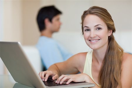 simsearch:400-04412244,k - Woman using a notebook while her fiance is sitting on a sofa in their living room Stock Photo - Budget Royalty-Free & Subscription, Code: 400-05746734
