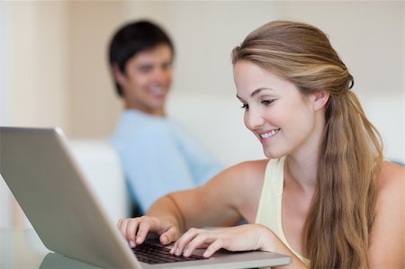 simsearch:400-04412244,k - Woman using a notebook while her fiance is sitting on a couch in their living room Stock Photo - Budget Royalty-Free & Subscription, Code: 400-05746735