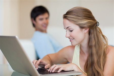 simsearch:400-04412244,k - Woman using a laptop while her husband is sitting on a sofa in their living room Stock Photo - Budget Royalty-Free & Subscription, Code: 400-05746736