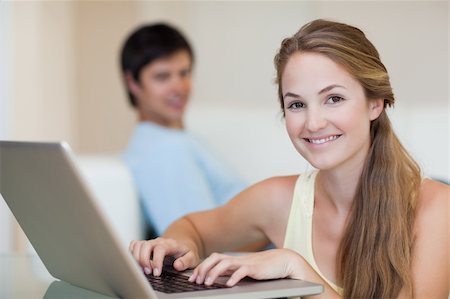 simsearch:400-04412244,k - Woman using a laptop while her husband is sitting on a couch in their living room Stock Photo - Budget Royalty-Free & Subscription, Code: 400-05746737
