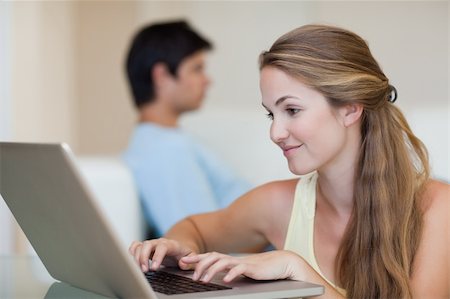 simsearch:400-04412244,k - Woman using a laptop while her fiance is sitting on a couch in their living room Stock Photo - Budget Royalty-Free & Subscription, Code: 400-05746731