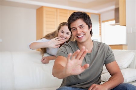 Couple waving at the camera in their living room Stock Photo - Budget Royalty-Free & Subscription, Code: 400-05746816