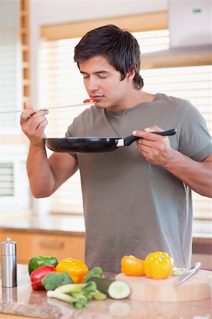 simsearch:400-05744780,k - Portrait of a young man tasting his meal in his kitchen Stock Photo - Budget Royalty-Free & Subscription, Code: 400-05746862