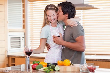 simsearch:400-05740111,k - Lovely couple drinking red wine while kissing in their kitchen Stock Photo - Budget Royalty-Free & Subscription, Code: 400-05746875