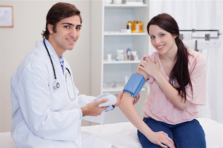 simsearch:400-05748252,k - Smiling male doctor taking patients blood pressure Stock Photo - Budget Royalty-Free & Subscription, Code: 400-05747055