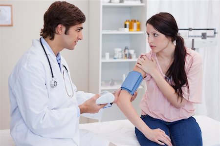 simsearch:400-05748252,k - Young doctor checking patients blood pressure Stock Photo - Budget Royalty-Free & Subscription, Code: 400-05747052