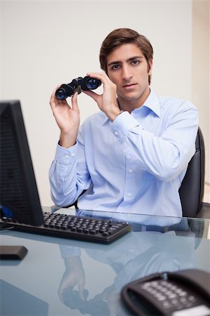 simsearch:400-05748170,k - Young businessman with binoculars in his office Stock Photo - Budget Royalty-Free & Subscription, Code: 400-05747474