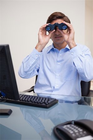 simsearch:400-05748170,k - Young businessman looking through binoculars in his office Stock Photo - Budget Royalty-Free & Subscription, Code: 400-05747475