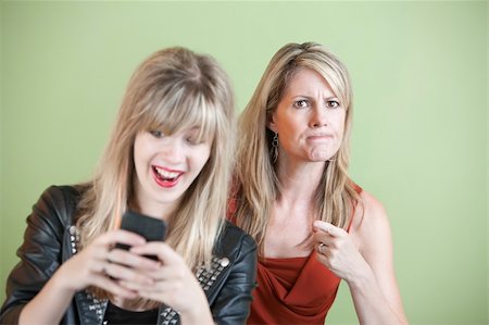 simsearch:400-05918419,k - Upset woman with laughing teen on cell phone Stock Photo - Budget Royalty-Free & Subscription, Code: 400-05747806