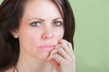 simsearch:400-05388090,k - Concerned young Caucasian woman on green background with fingers to chin Stock Photo - Budget Royalty-Free & Subscription, Code: 400-05747853