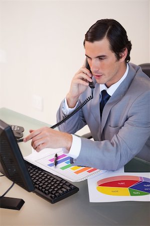 simsearch:400-05748170,k - Young businessman talking on the phone while working on statistics Stock Photo - Budget Royalty-Free & Subscription, Code: 400-05748144
