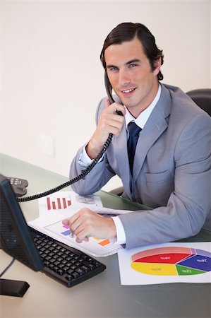 simsearch:400-05748170,k - Smiling young businessman on the phone working on statistics Stock Photo - Budget Royalty-Free & Subscription, Code: 400-05748145