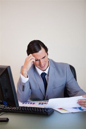simsearch:400-05748170,k - Young businessman getting a headache from looking at paperwork Stock Photo - Budget Royalty-Free & Subscription, Code: 400-05748149