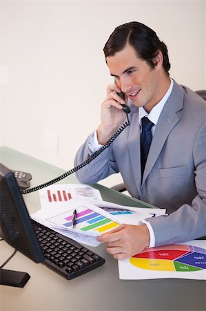 simsearch:400-05748170,k - Smiling young businessman talking about statistics on the phone Stock Photo - Budget Royalty-Free & Subscription, Code: 400-05748143