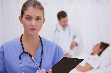 simsearch:400-05748252,k - Surgeon standing in patients room with colleague and patient behind her Stock Photo - Budget Royalty-Free & Subscription, Code: 400-05748263