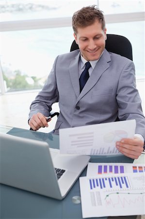 simsearch:400-05748170,k - Smiling businessman at his desk looking at market research results Stock Photo - Budget Royalty-Free & Subscription, Code: 400-05748285