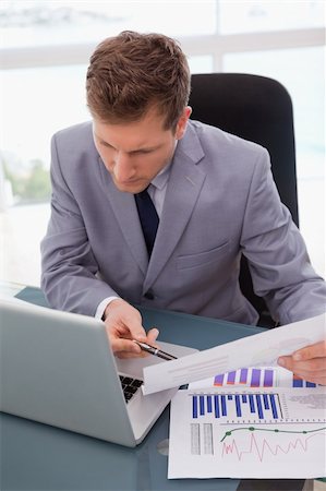 simsearch:400-05748170,k - Businessman looking at his laptop while working on statistics Stock Photo - Budget Royalty-Free & Subscription, Code: 400-05748281