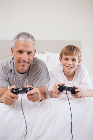 simsearch:400-05751526,k - Portrait of a boy and his father playing video games in a bedroom Stock Photo - Budget Royalty-Free & Subscription, Code: 400-05749400