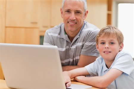 simsearch:400-05749727,k - Young boy and his father using a laptop in a kitchen Foto de stock - Super Valor sin royalties y Suscripción, Código: 400-05749514