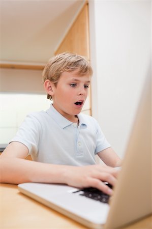 face to internet technology - Portrait of a surprised boy using a notebook in a kitchen Stock Photo - Budget Royalty-Free & Subscription, Code: 400-05749524