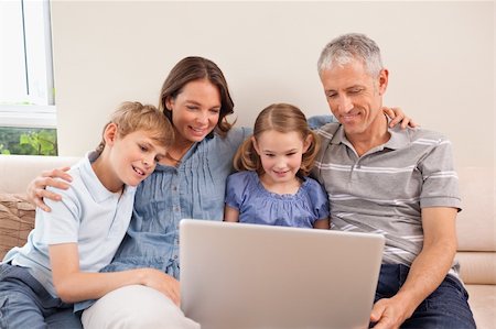 simsearch:400-05749633,k - Family sitting on a sofa using a notebook in a living room Stock Photo - Budget Royalty-Free & Subscription, Code: 400-05749597