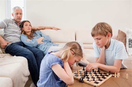 simsearch:400-05749633,k - Children playing chess in front of their parents in a living room Stock Photo - Budget Royalty-Free & Subscription, Code: 400-05749614