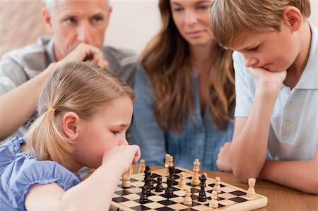 simsearch:400-05749633,k - Focused children playing chess in front of their parents in a living room Stock Photo - Budget Royalty-Free & Subscription, Code: 400-05749615