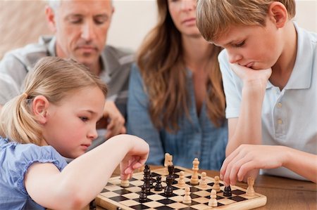 simsearch:400-05749633,k - Focused siblings playing chess in front of their parents in a living room Stock Photo - Budget Royalty-Free & Subscription, Code: 400-05749616