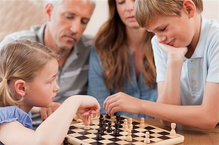 simsearch:400-05749633,k - Close up of siblings playing chess in front of their parents in a living room Stock Photo - Budget Royalty-Free & Subscription, Code: 400-05749617