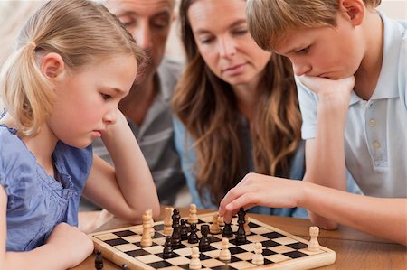 simsearch:400-05749633,k - Close up of serious children playing chess in front of their parents in a living room Stock Photo - Budget Royalty-Free & Subscription, Code: 400-05749619