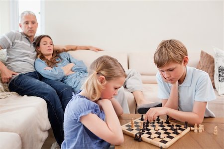 simsearch:400-05749633,k - Siblings playing chess in front of their parents in a living room Stock Photo - Budget Royalty-Free & Subscription, Code: 400-05749613