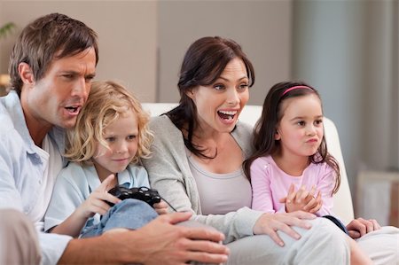simsearch:400-05749633,k - Cheerful family playing video games together in a living room Stock Photo - Budget Royalty-Free & Subscription, Code: 400-05749660