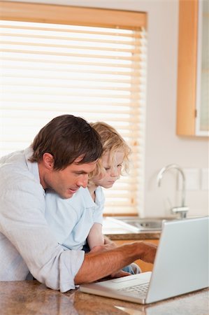 simsearch:400-05749727,k - Portrait of a boy and his father using a laptop together in a kitchen Foto de stock - Super Valor sin royalties y Suscripción, Código: 400-05749724