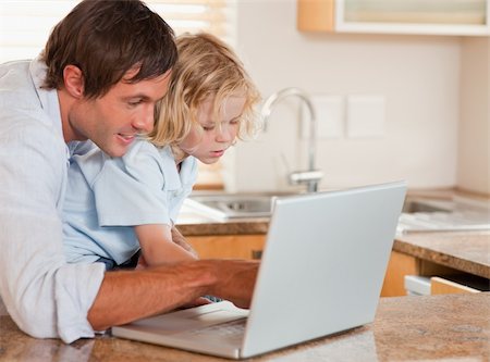 simsearch:400-05749727,k - Cute boy and his father using a laptop together in a kitchen Foto de stock - Super Valor sin royalties y Suscripción, Código: 400-05749725