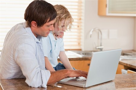 simsearch:400-05749727,k - Boy and his father using a laptop together in a kitchen Foto de stock - Super Valor sin royalties y Suscripción, Código: 400-05749721