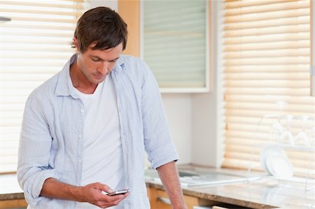 simsearch:400-06632132,k - Man using a mobile phone in his kitchen Stock Photo - Budget Royalty-Free & Subscription, Code: 400-05749733