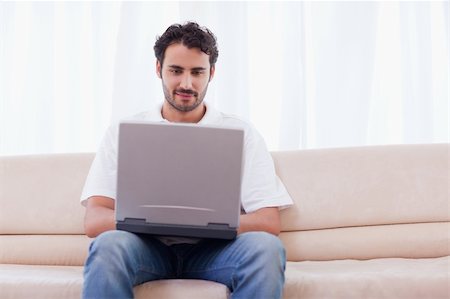 face to internet technology - Man using a laptop in his living room Photographie de stock - Aubaine LD & Abonnement, Code: 400-05741519