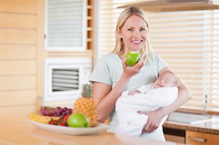 premature - Smiling young woman with an apple and her baby on her arms Stock Photo - Budget Royalty-Free & Subscription, Code: 400-05741513