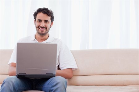 simsearch:400-04412244,k - Smiling man using a laptop in his living room Stock Photo - Budget Royalty-Free & Subscription, Code: 400-05741526