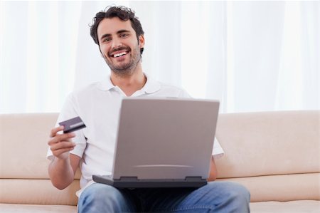 face to internet technology - Smiling man buying online in his living room Stock Photo - Budget Royalty-Free & Subscription, Code: 400-05741528